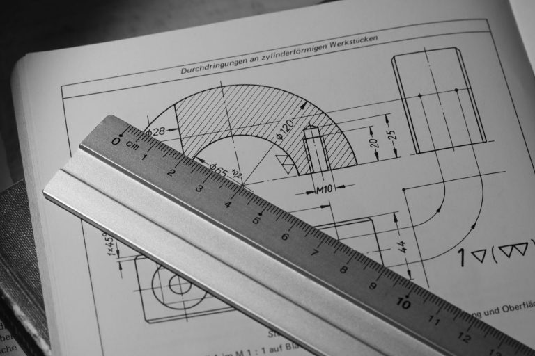 Metal ruler across a mechanical section drawing with dimensions